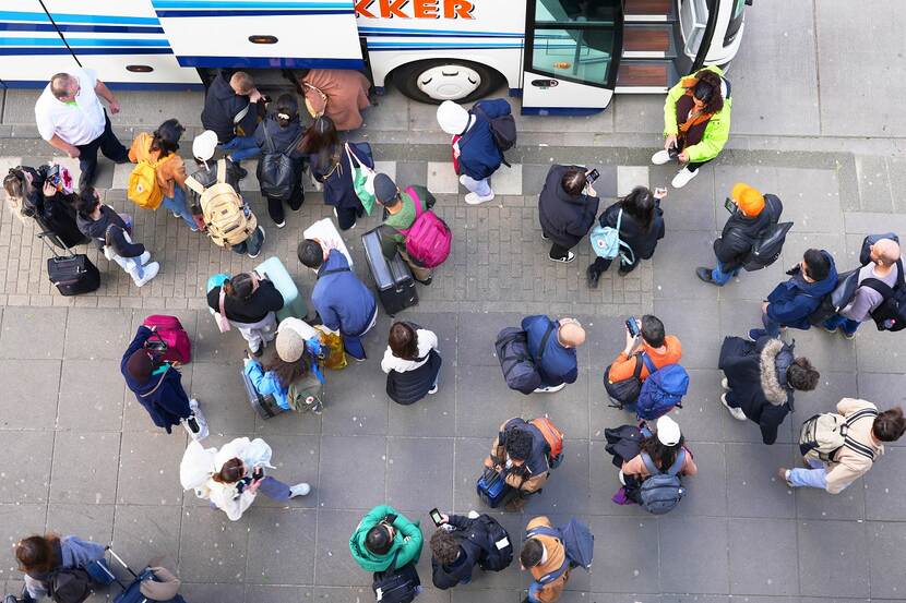 Busreizigers laden hun koffers in laadruimte bus